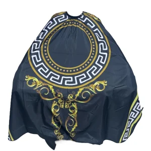 Capa de corte profesional Ref 005 con diseño de medallón barroco dorado y grecas blancas sobre tela negra de alta calidad.