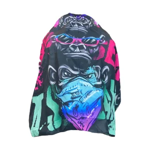 Capa de barbería profesional XL modelo PB-024 con diseño de gorila con gafas de sol, bandana azul y salpicaduras de pintura neón sobre fondo negro.